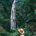 一位戴着帽子的女人站在瀑布前