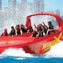 a group of people riding on a red speed boat in the water