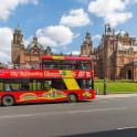a red double decker bus driving past a building
