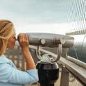 一位女士正在桥上用望远镜观察