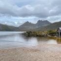 a house on the shore of a lake with mountains