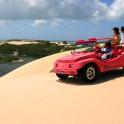 a group of people in a red jeep on a sand dune