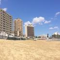 a sandy beach with tall buildings in the background