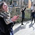 a group of women standing on a sidewalk looking at their cell phones