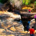 a group of people walking on rocks near a river