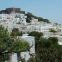 a group of white buildings on a hill with a castle