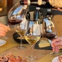 two people pouring wine into wine glasses on a table