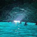 a group of people swimming in a blue cave