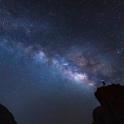 a starry sky with a person standing on a mountain