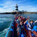 a group of people on a boat in the water with a lighthouse