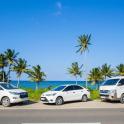 a group of three cars parked next to the beach