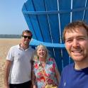 two men and a woman standing next to a blue object on the beach