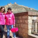 two girls in pink jackets standing next to a wall