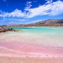 a beach with clear water and mountains in the background