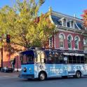 a blue bus driving down a street in front of a building