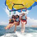 three girls in life vests are riding on a parachute in the ocean