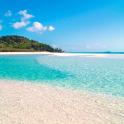 一片海水清澈的海滩，背景中有一座岛屿