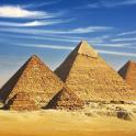 a group of pyramids in the desert under a blue sky