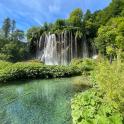 a waterfall in a forest with a body of water