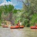 three people are riding on rafts on a river