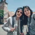two women standing next to each other in front of a clock tower