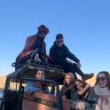 a group of people sitting on the back of a truck in the desert