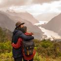 a man and woman standing on a hill looking at a valley