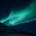 an aurora in the sky over a mountain