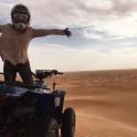 a man standing on a wheeler in the desert