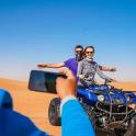 two people riding a quad bike in the desert