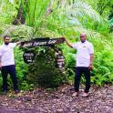 two men standing next to a sign in a forest