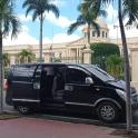 a black van parked in front of a building with palm trees