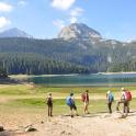 a group of people standing on a hill near a lake