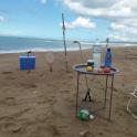 a table and chairs on a beach with a racket