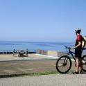 a man standing next to a bike on the beach