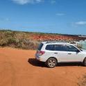 a white suv parked on a dirt road next to the ocean