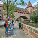 a group of people standing on a bridge in front of a castle