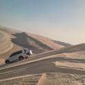 a white car driving down a sand dune