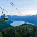two gondolas flying over a lake in the mountains
