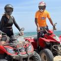 a man and a woman on atvs on the beach