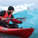 a man in a kayak in front of an iceberg