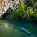 three boats in a river next to a mountain
