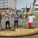 Un grupo de personas de pie alrededor de un barco en la playa.