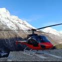 a red helicopter parked in front of a mountain