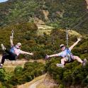 two people are jumping in the air on zip lines