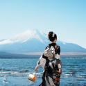 a woman standing on the beach with a mountain in the background