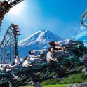a group of people riding on a roller coaster with a mountain in the background