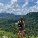 a woman standing on top of a mountain looking at a valley