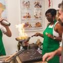 a group of people cooking food in a pan on a stove