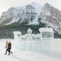 two people walking past an ice sculpture in the snow